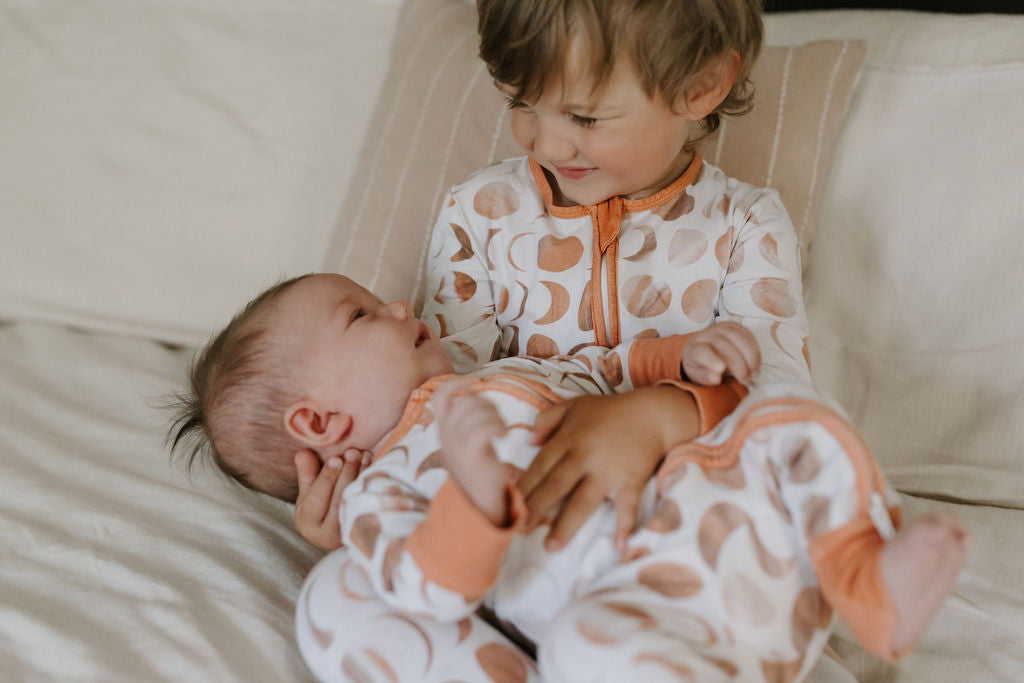 Toddler holding baby in Phases print Sunny & KO pajamas